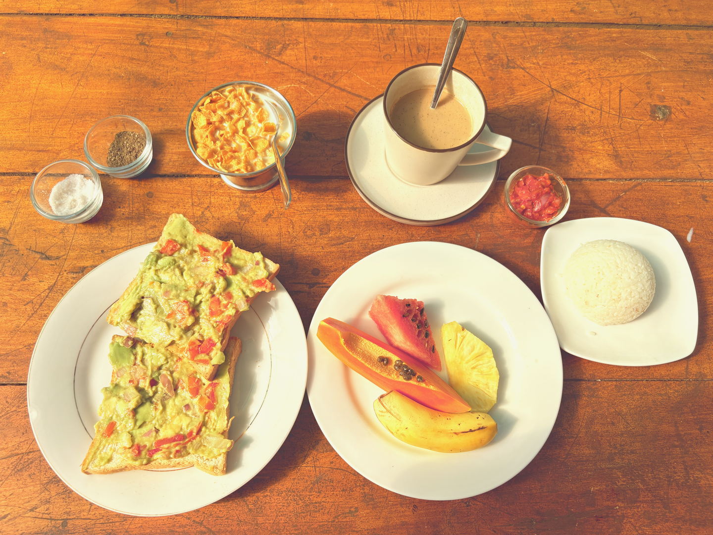 A breakfast plate on a scarred wooden table in green light, with the ridge beyond the railing.