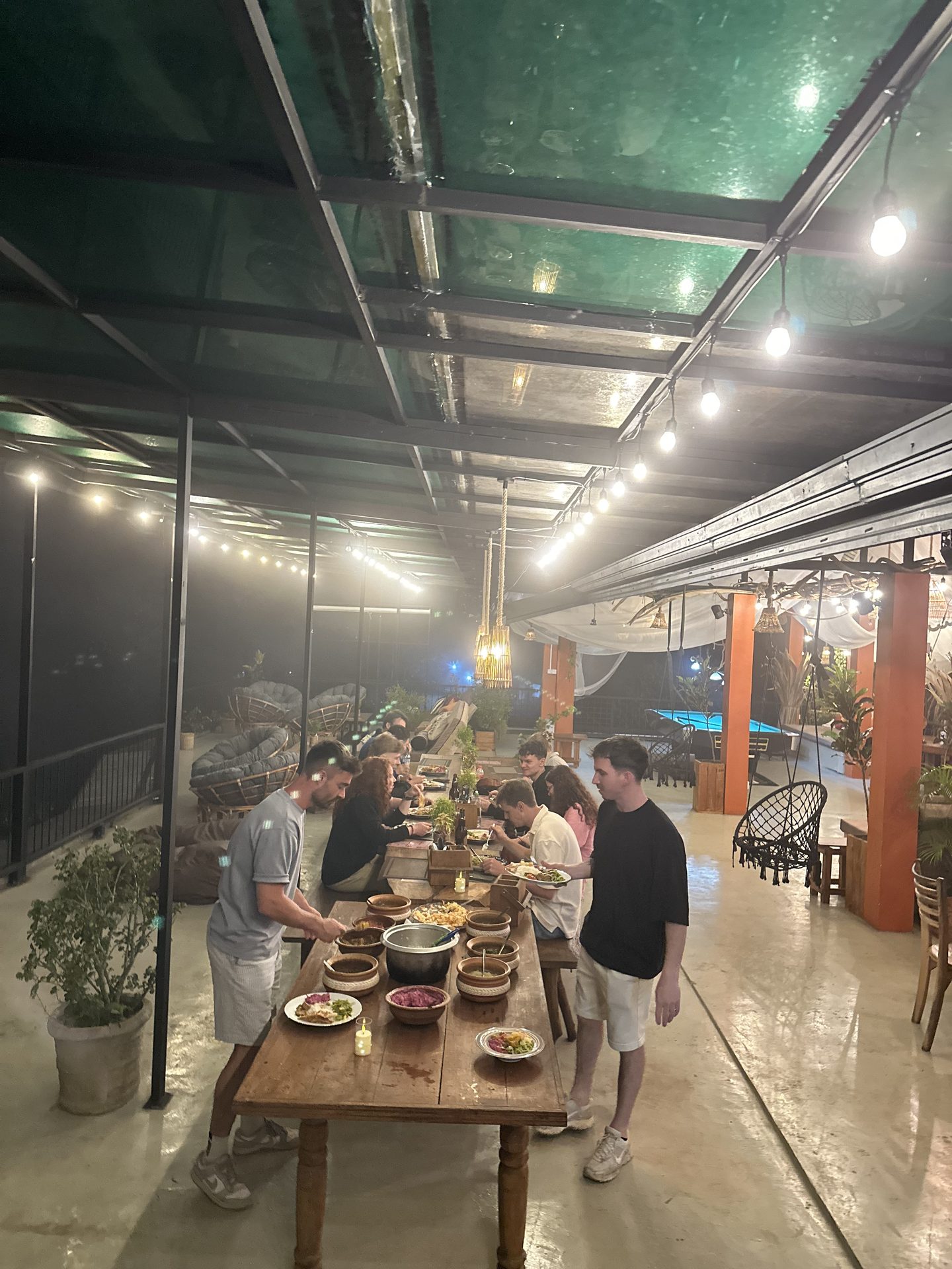 Guests eating a buffet family dinner together at the long tables on the rooftop terrace.