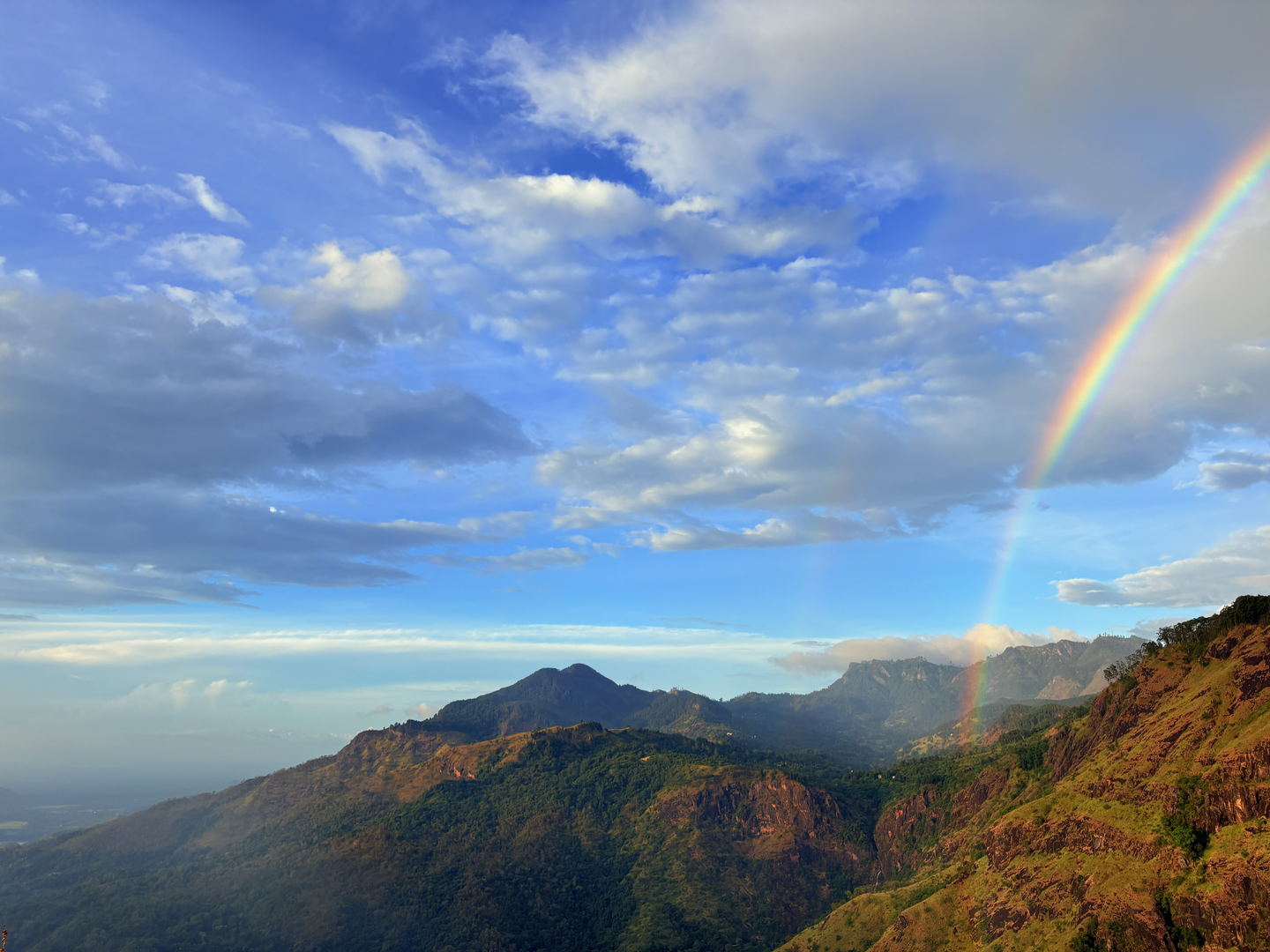 A wide view across the gap from a ridge, the valley floor in shadow and ranges of hills going back into haze.
